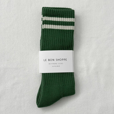 Green sock with white stripes and 'Le Bon Shoppe' label on a light gray background