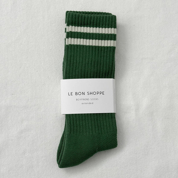 Green sock with white stripes and 'Le Bon Shoppe' label on a light gray background