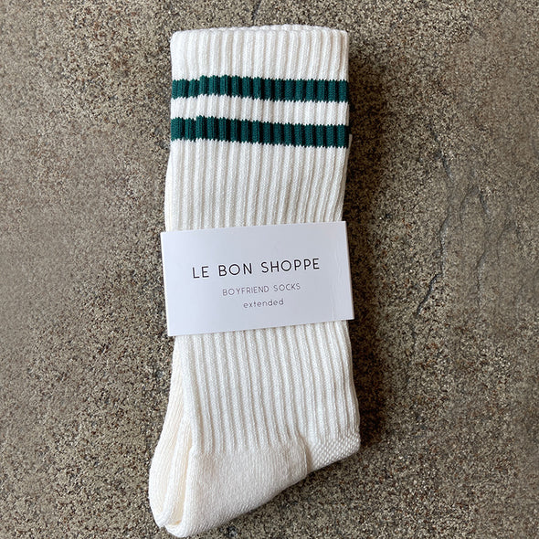 White sock with green stripes and 'Le Bon Shoppe' label on a textured surface