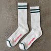 White socks with green stripes and red text on a gray surface