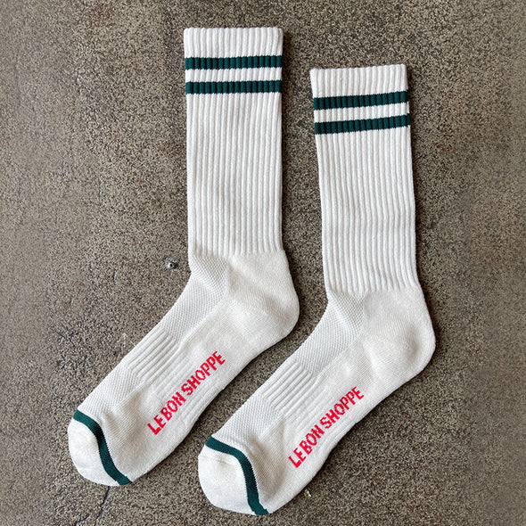 White socks with green stripes and red text on a gray surface
