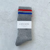 Gray sock with red and blue stripes and a label on a light gray background