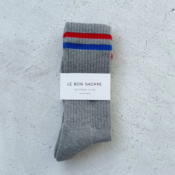 Gray sock with red and blue stripes and a label on a light gray background
