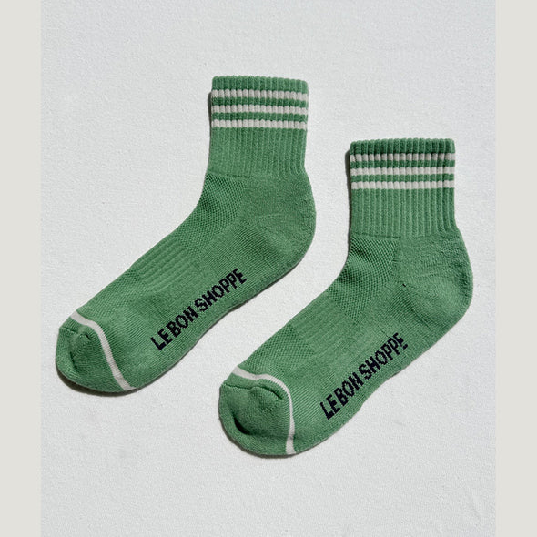 Green socks with striped cuffs and toes on a light gray background