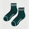Pair of green socks with white stripes and 'Le Bon Shoppe' branding on a light gray background