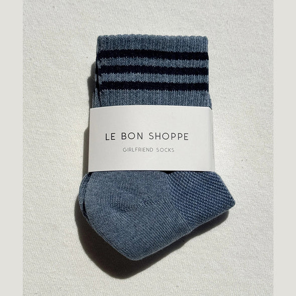 Pair of blue socks with three black stripes on a light gray background, featuring 'Le Bon Shoppe' label.