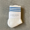 Pair of white socks with blue stripes and a visible brand label on a gray surface