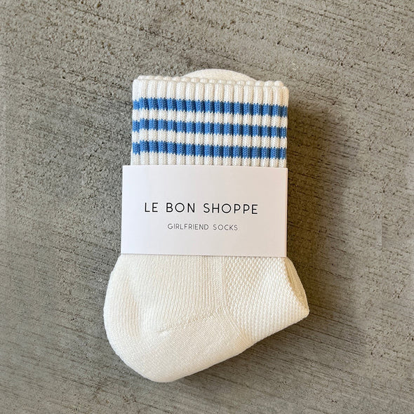 Pair of white socks with blue stripes and a visible brand label on a gray surface