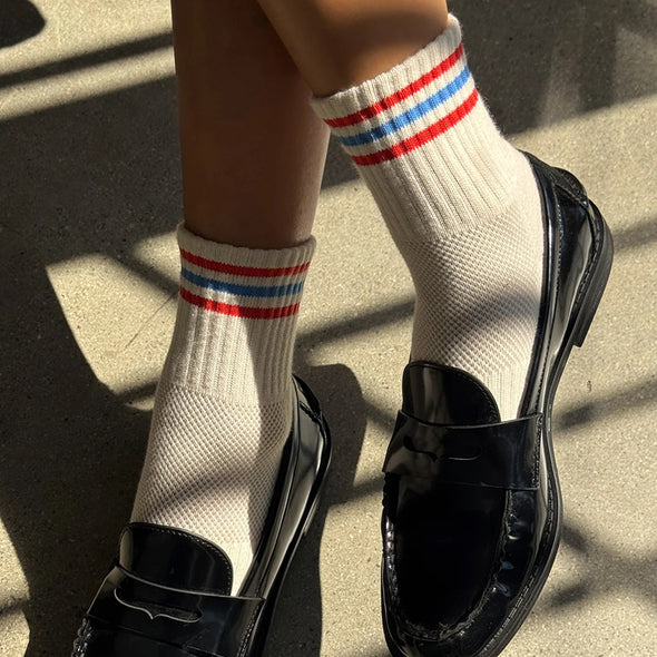 feet wearing black shoes and Le Bon Shoppe Girlfriend Socks in white with 3 red and blue stripes