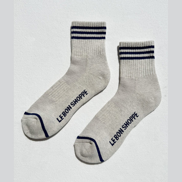 Pair of gray socks with blue stripes and 'Le Bon Shoppe' branding on a white background