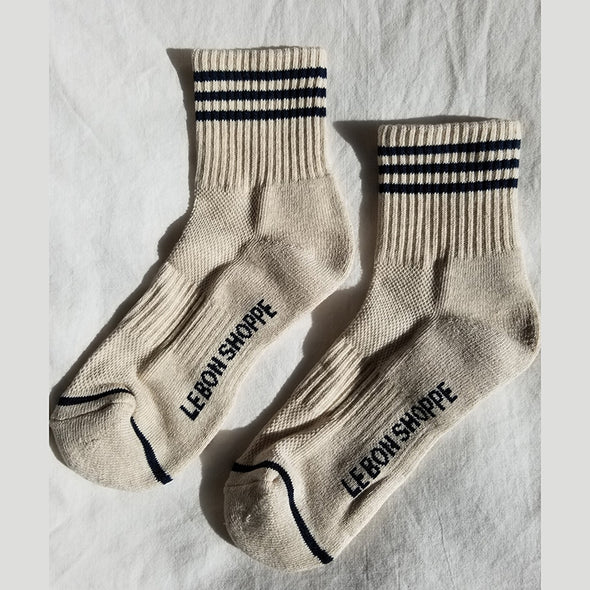 Pair of beige socks with black stripes and 'LEBON SHOPPE' branding on a light gray background
