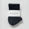 Pair of dark gray socks with a white label on a light gray background