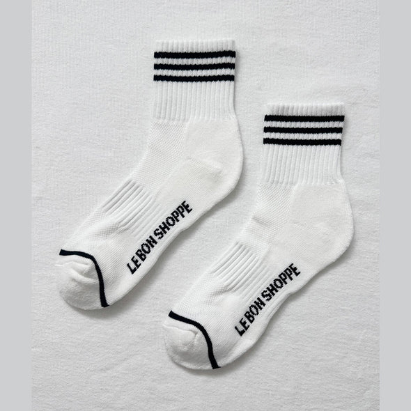White socks with black stripes and 'Le Bon Shoppe' branding on a light gray background
