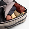 Open suitcase with folded clothes inside on a white background