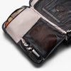 Open travel bag with compartments containing various items on a white background