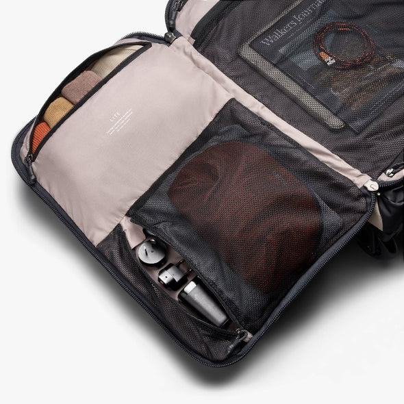 Open travel bag with compartments containing various items on a white background
