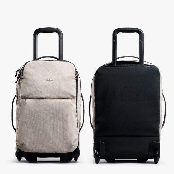Two rolling suitcases, one beige and one black, on a white background.
