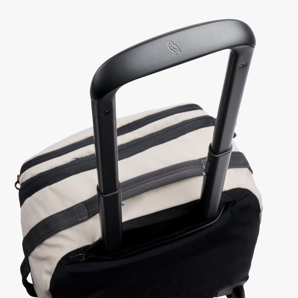 Black suitcase handle on a striped suitcase with a visible brand logo.