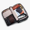 Open suitcase with neatly packed clothes on a white background