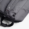 Gray checkered bag with black straps on a white background