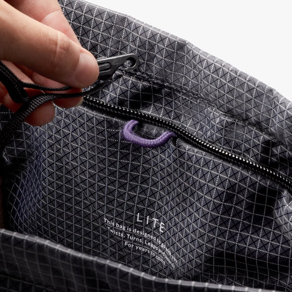 Close-up of a person opening a black geometric-patterned bag with 'LITE' branding.