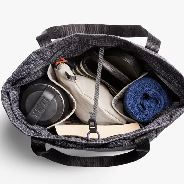 Lite Totepack by Bellroy Arcade Gray with items including a blue towel, black container, and beige bag on a white background