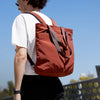 Person wearing a Clay Bellroy Tote backpack against a clear blue sky