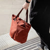 Person holding a clay Bellroy  tote bag on a sidewalk