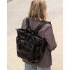 Person wearing a black backpack on a neutral background