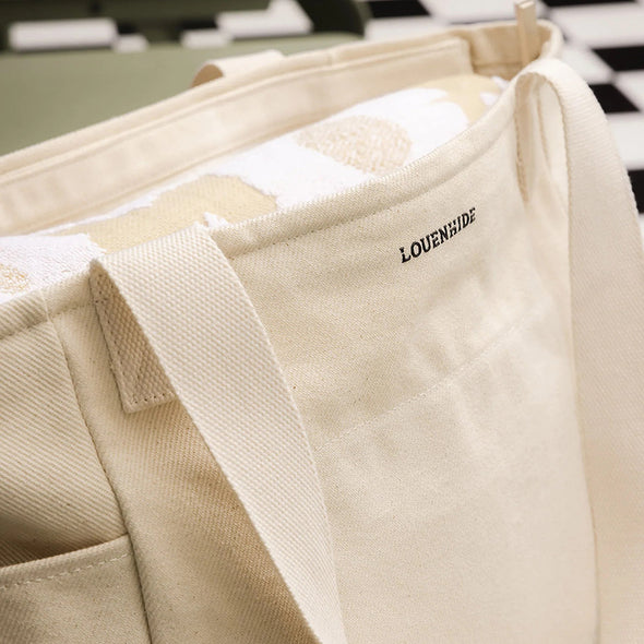 Close-up of a beige bag with 'LOUENHIDE' branding on a checkered floor.