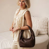Woman holding a brown handbag in a living room setting
