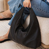 Person holding a black handbag on a textured surface