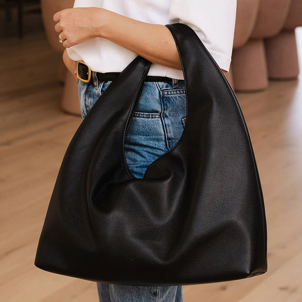 Person holding a black handbag with a blurred background