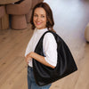 Woman holding a black bag indoors with a neutral background