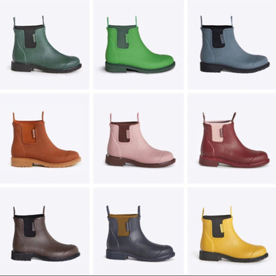 A collection of 'Merry People' gumboots in various colors displayed in three rows, with the brand's branding visible on the boots.
