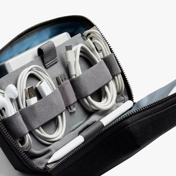 Organized set of electronic cables and devices in a black carrying case on a white background Tech Kit by Bellroy