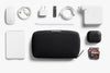 Collection of electronic accessories including a black Tech Kit by Bellroy, power adapter, and memory cards on a white background.