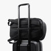 Black duffel bag on top of a suitcase with a white background