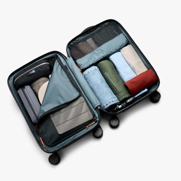 Open suitcase with neatly folded clothes inside on a white background