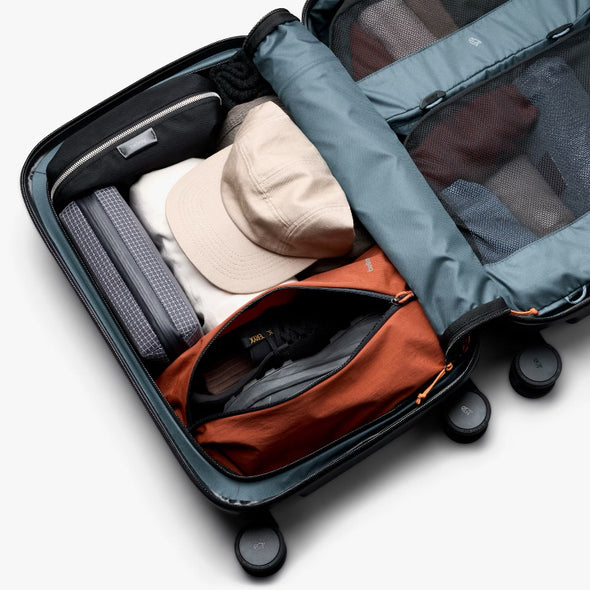 Open suitcase with clothes and a hat on a white background