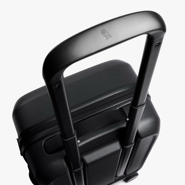 Black suitcase with handle and visible brand logo on a white background