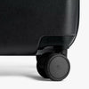Close-up of a black suitcase wheel on a white background