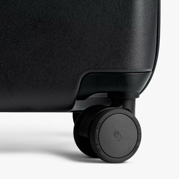 Close-up of a black suitcase wheel on a white background