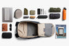 Collection of travel items including a backpack, laptop, phone, and other accessories on a white background.