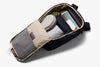 Open travel bag with compartments containing various items on a white background