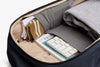 Open suitcase with clothes, a keyboard, and a notebook inside