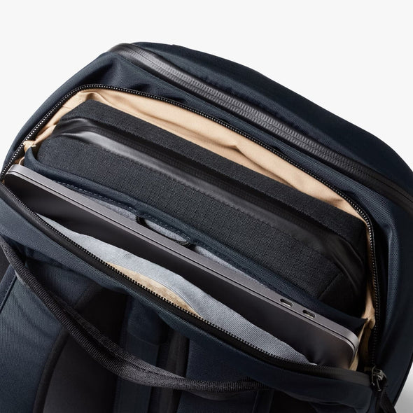 Navy backpack with a compartment holding a laptop on a white background