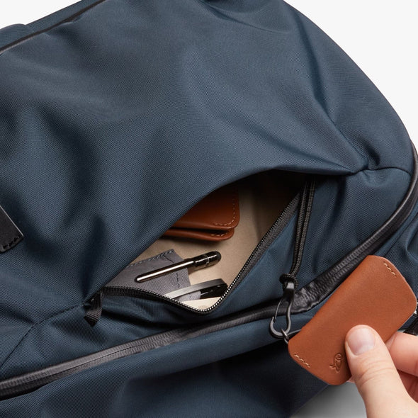 Blue backpack with a brown leather tag being held open by a hand