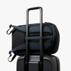 Navy backpack with a shoulder strap over a suitcase on a white background