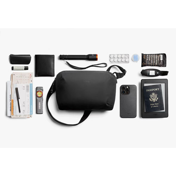 Black travel bag with various travel items on a white background